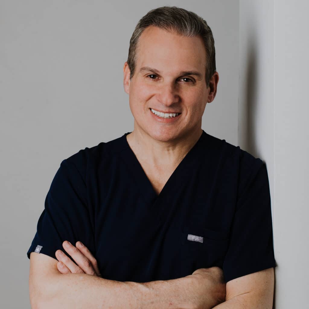 Dr. Leonard J. Resnick a trusted dentist in Great Neck standing with arms crossed and smiling at TruYou Dental