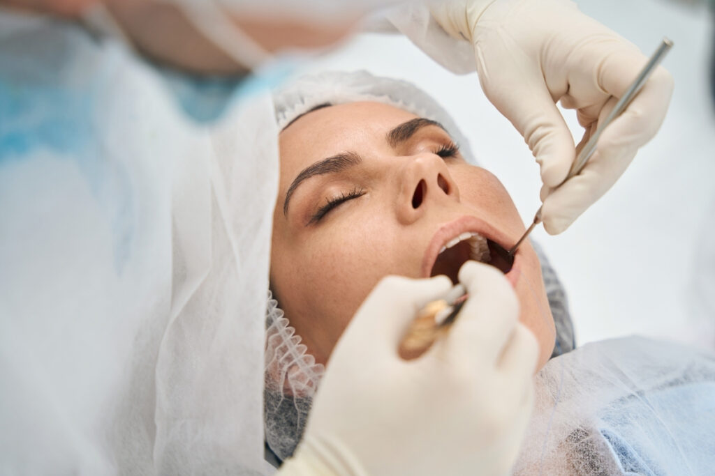 Dentist examining patient's teeth during dental checkup at Great Neck practice.