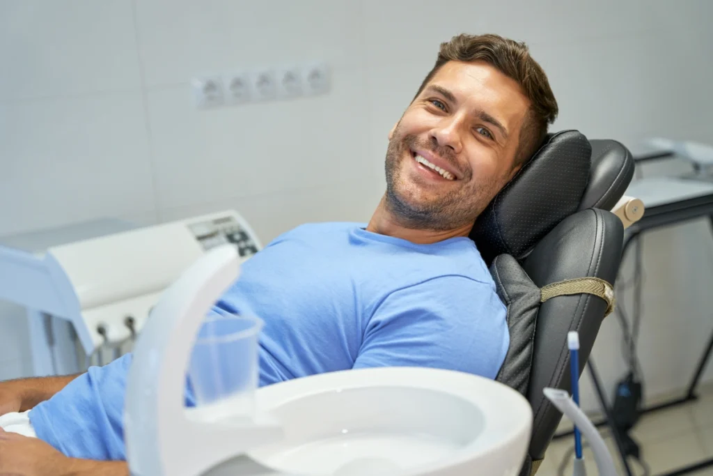 Smiling male patient relaxed in dental chair during restorative treatment consultation.